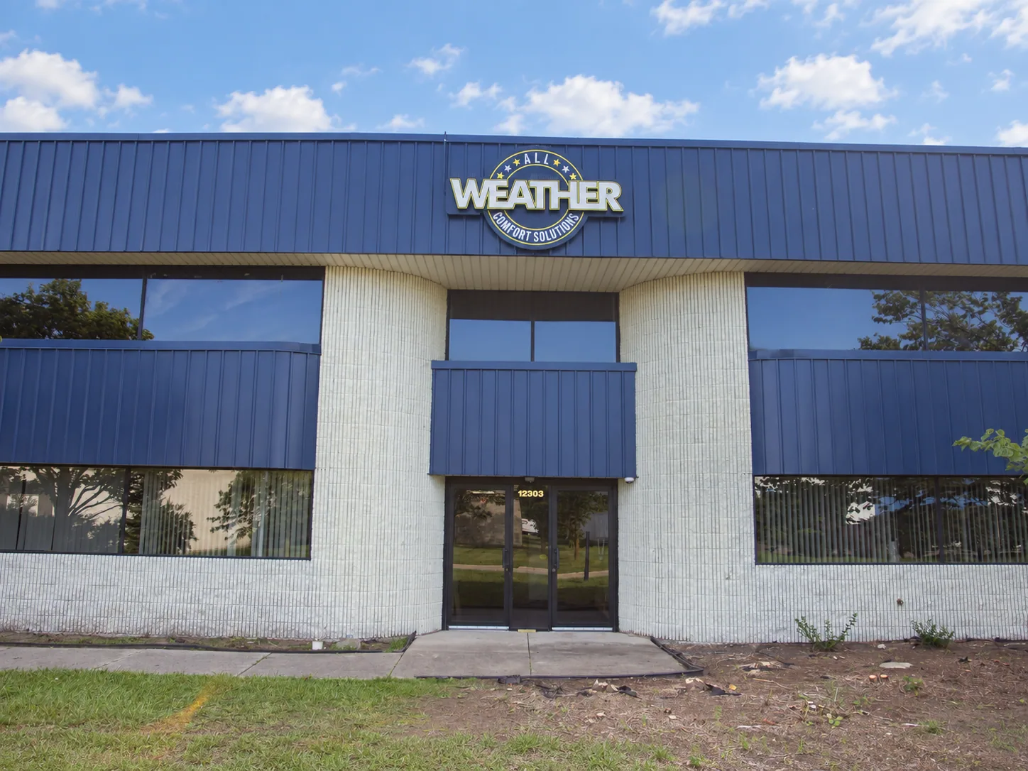 The All Weather building entrance beneath its blue awning and company sign