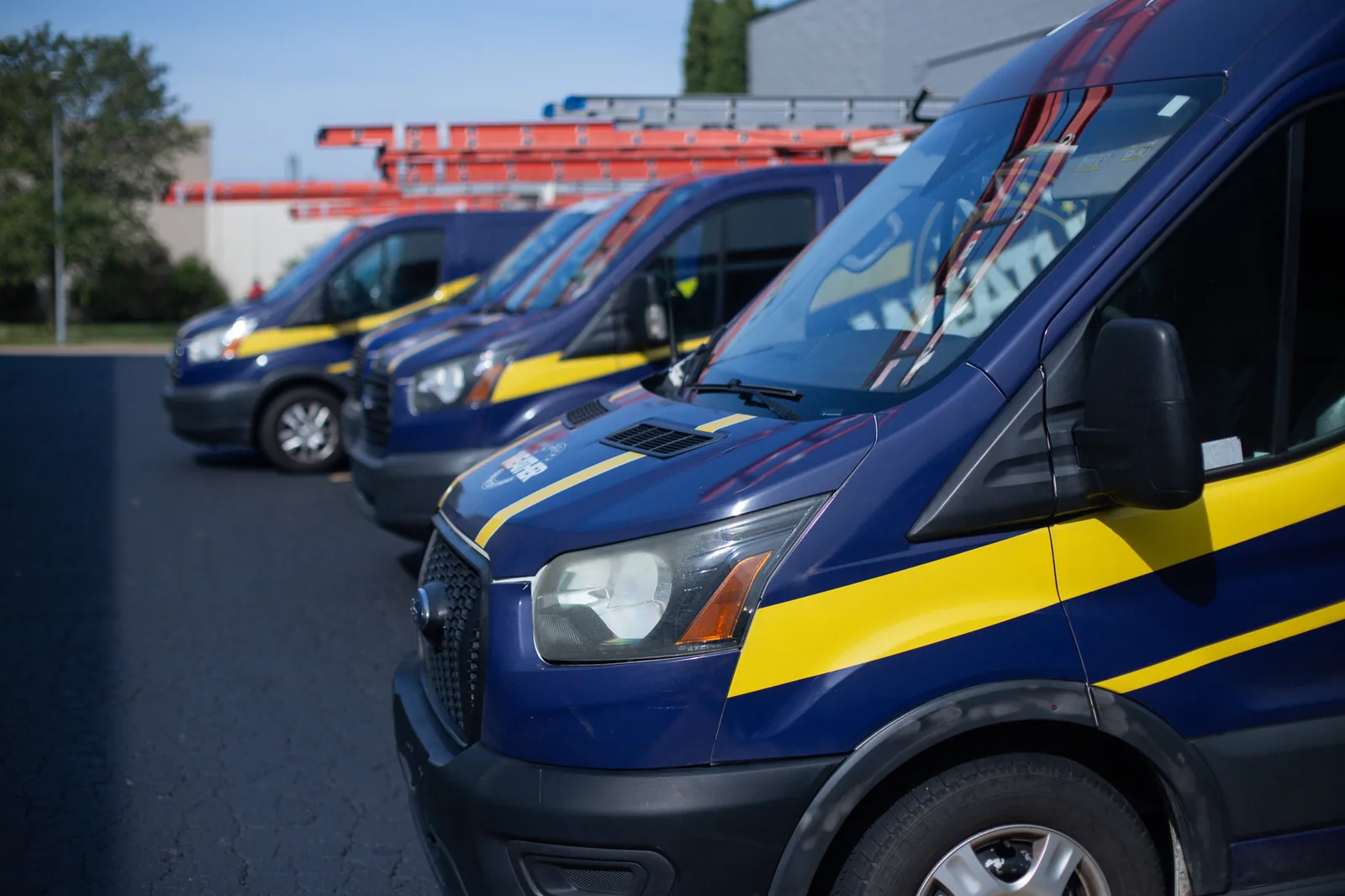 A row of All Weather Comfort Solutions service vans with navy and gold branding