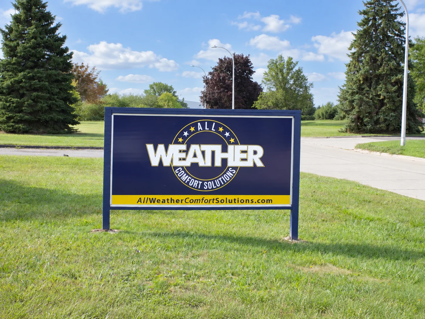 The navy and gold All Weather sign on the lawn beside the road