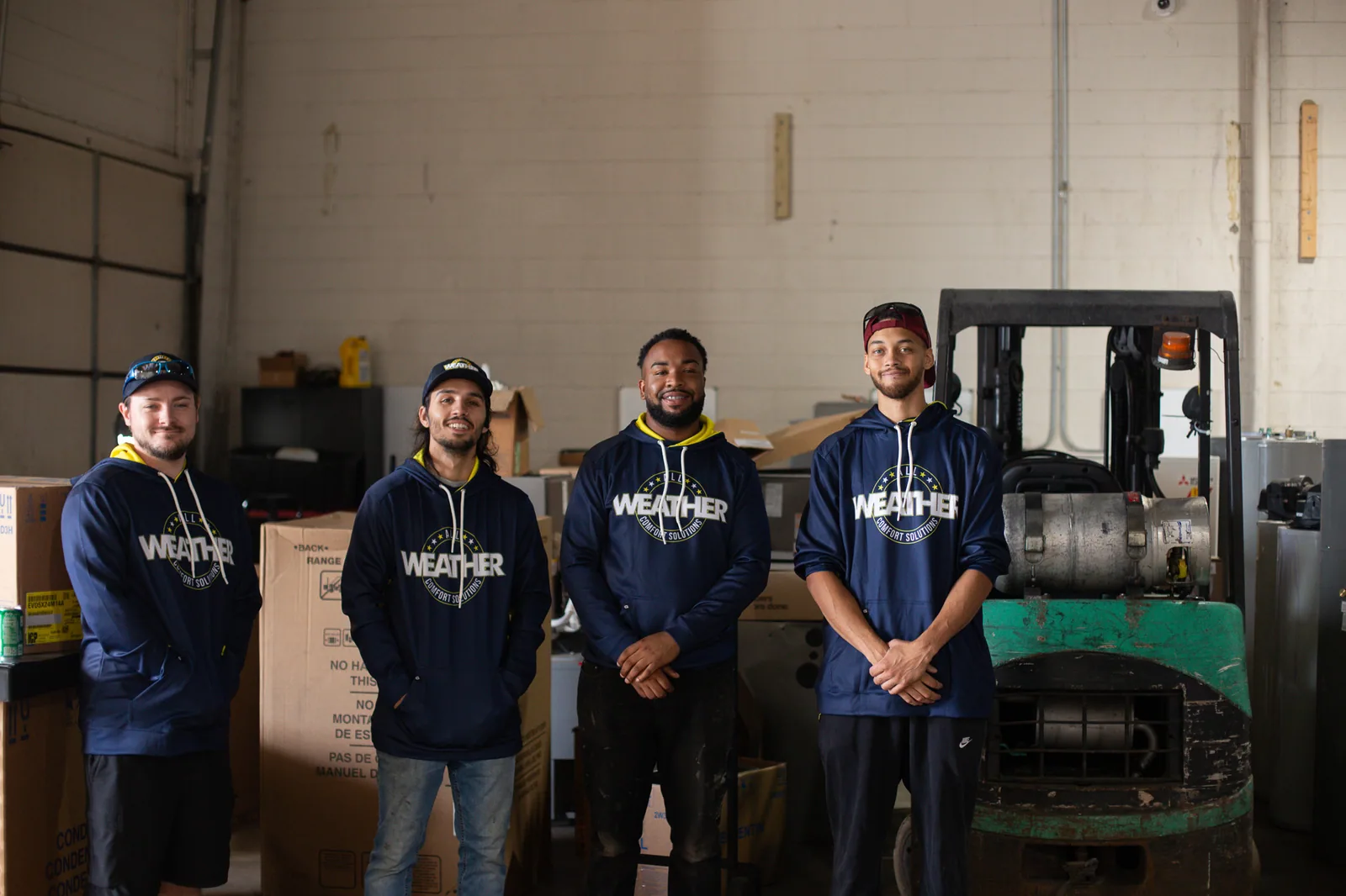 All Weather team members standing together by a forklift