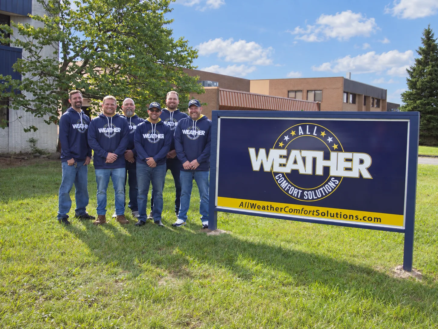 The All Weather Comfort Solutions team gathered outside by their roadside sign
